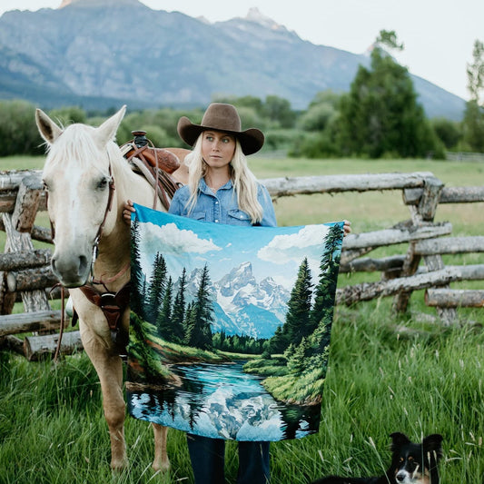 Woman beside a horse holding a wild rag of the teton mountain range, forest, and river print